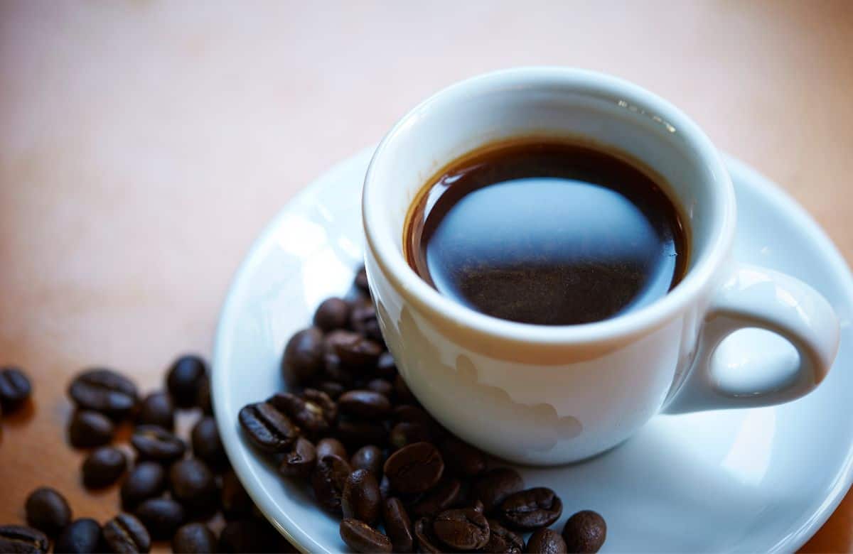 Small cup of coffee surrounded by coffee beans