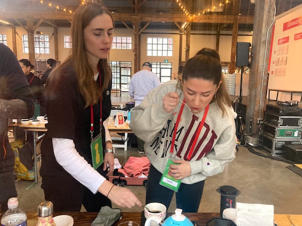 Sona Musa samples her coffee as her AeroPress coach looks on