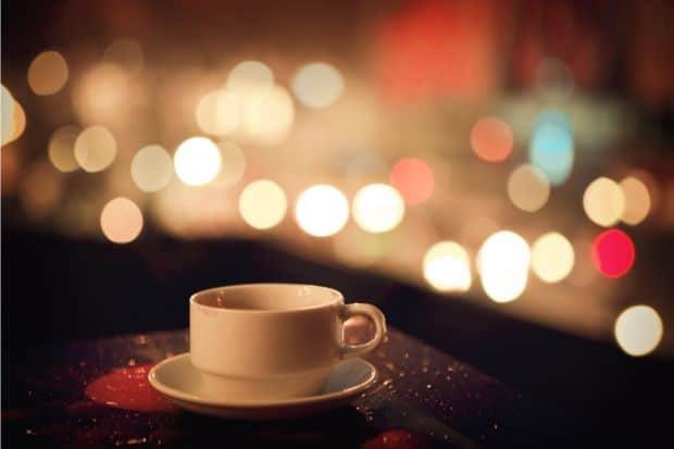 Coffee on a balcony with evening lights in the background