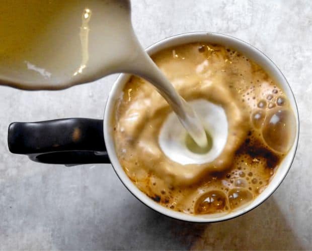 Heavy cream being poured into a cup of coffee