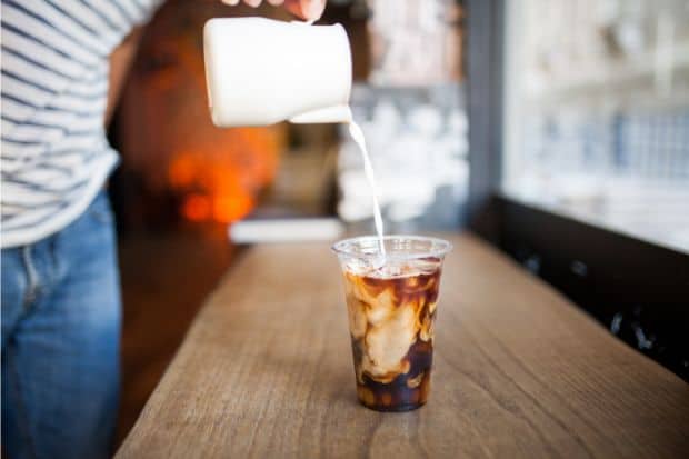 Heavy cream being poured into a cup of cold brew coffee