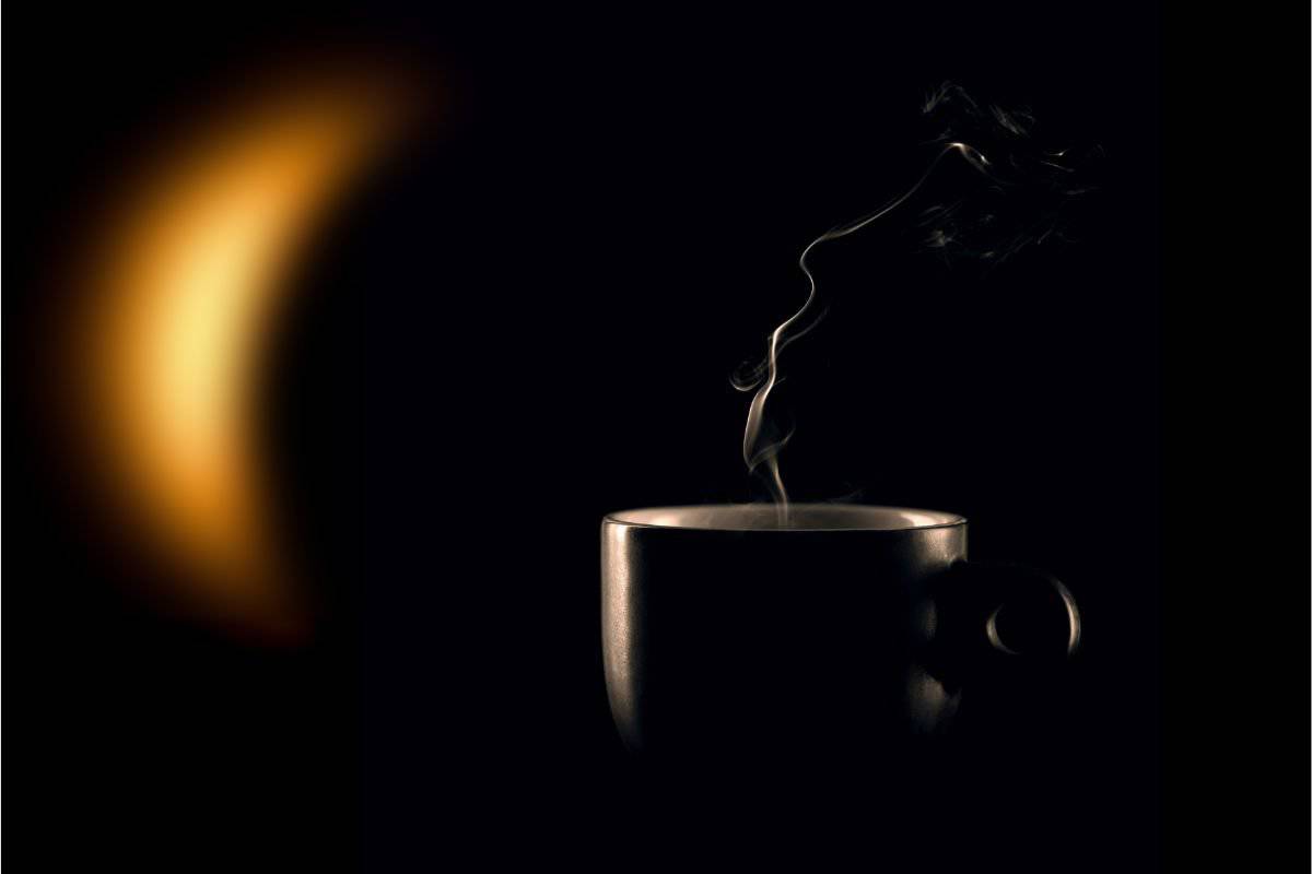 Steaming cup of coffee against a crescent moon backdrop