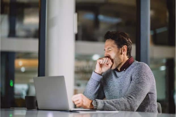 Man struggling to stay awake with coffee at his computer