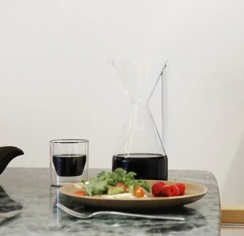 Yield Pourover Carafe on a table next to a salad and a cup of coffee