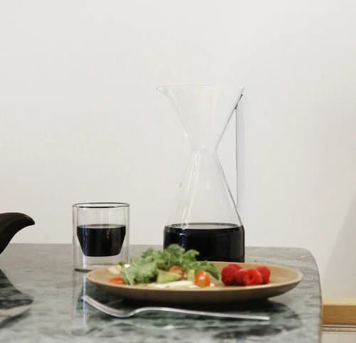 Yield Pourover Carafe on a table next to a salad and a cup of coffee