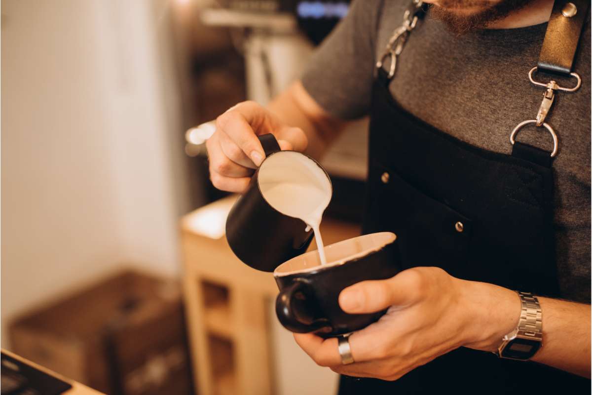 Barista carefully angling cup while pouring steamed milk