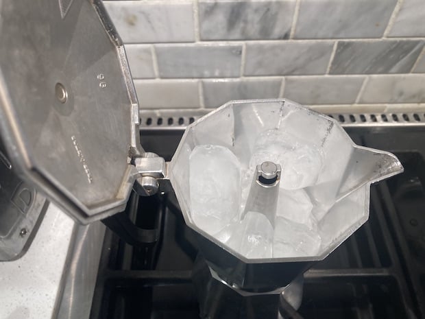 Moka pot on a burner with upper chamber half-filled with ice cubes