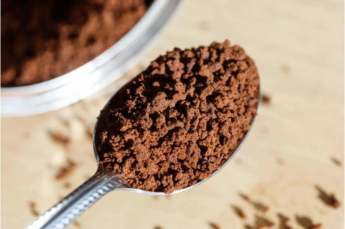 Instant coffee crystals on a teaspoon next to an instant coffee canister