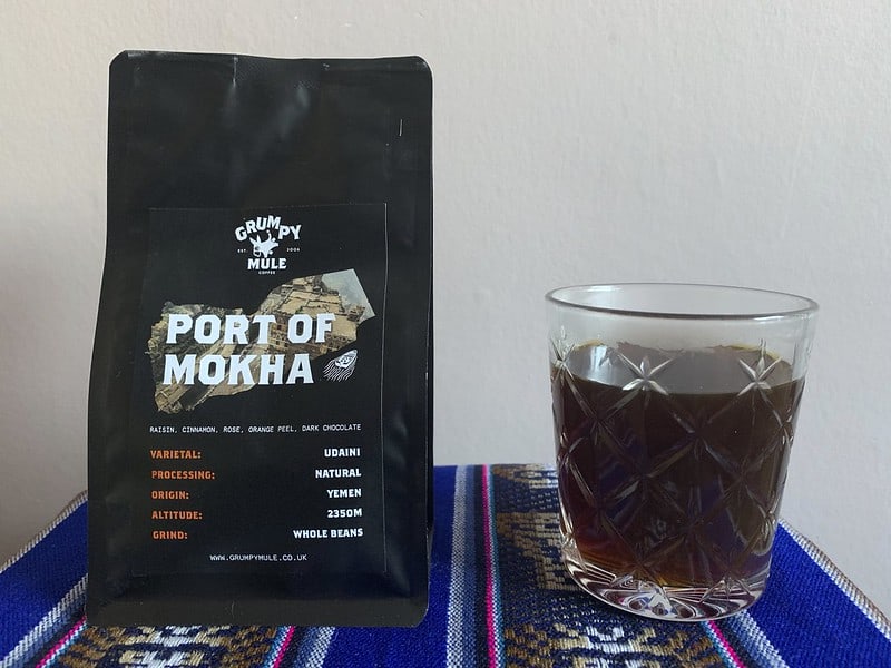 A bag of coffee beans labelled Port of Mokha next to a glass of brewed coffee