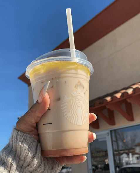 Hand holding up an Oleato coffee drink outside Starbucks