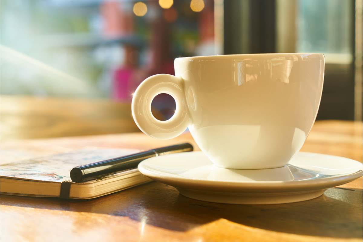 Journal and pen on a table next to a coffee cup