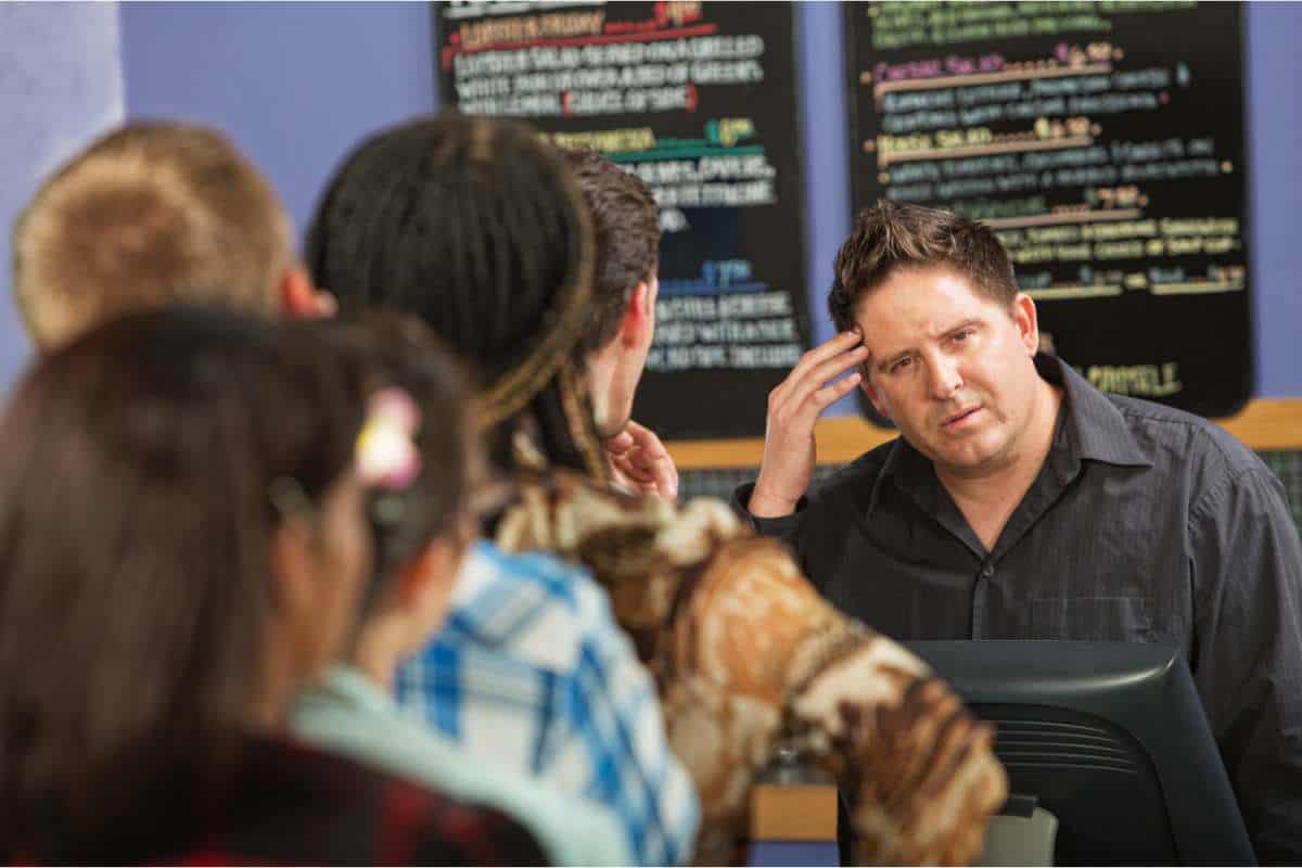 Puzzled barista behind the counter of a coffee shop with a long queue