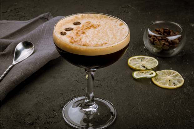 Cold brew coffee cocktail in a martini glass with three coffee beans floating on top