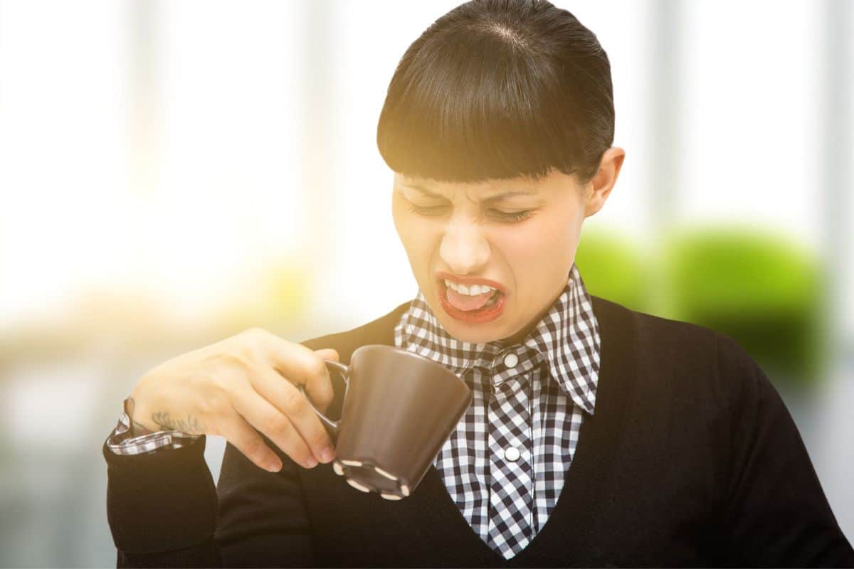 Woman grimacing at a cup of bad coffee