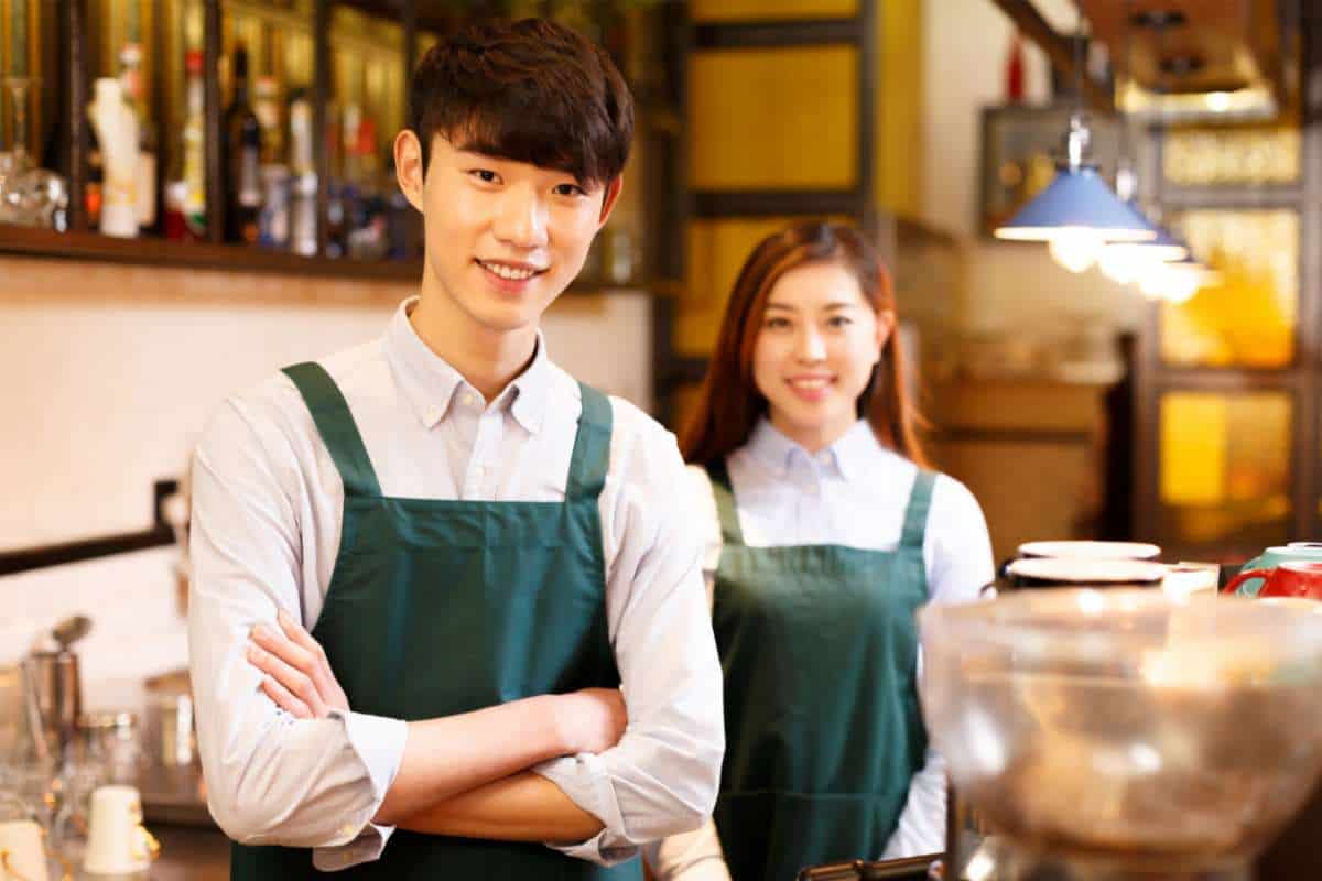 Two baristas smiling in anticipation behind a coffee shop counter