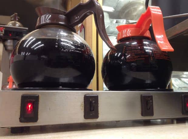 Coffee in round glass carafes resting on a burner in a diner