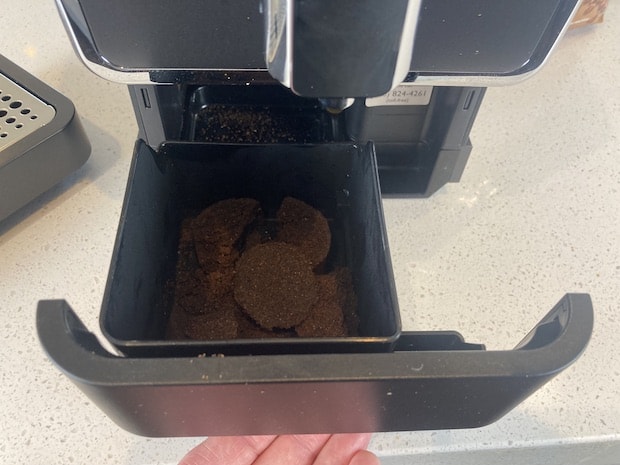 Hand sliding coffee grounds tray from beneath the Tchibo coffee machine