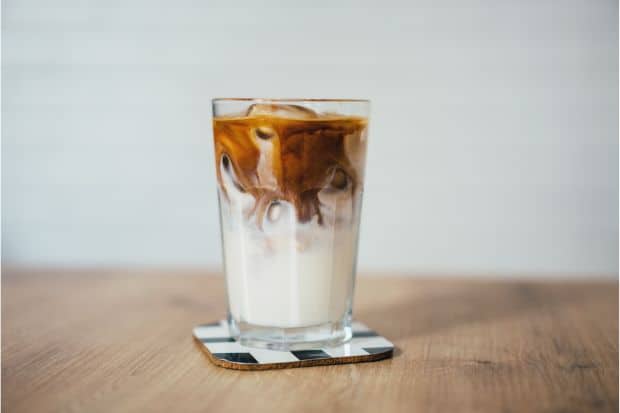 Glass of iced coffee with swirling cream inside
