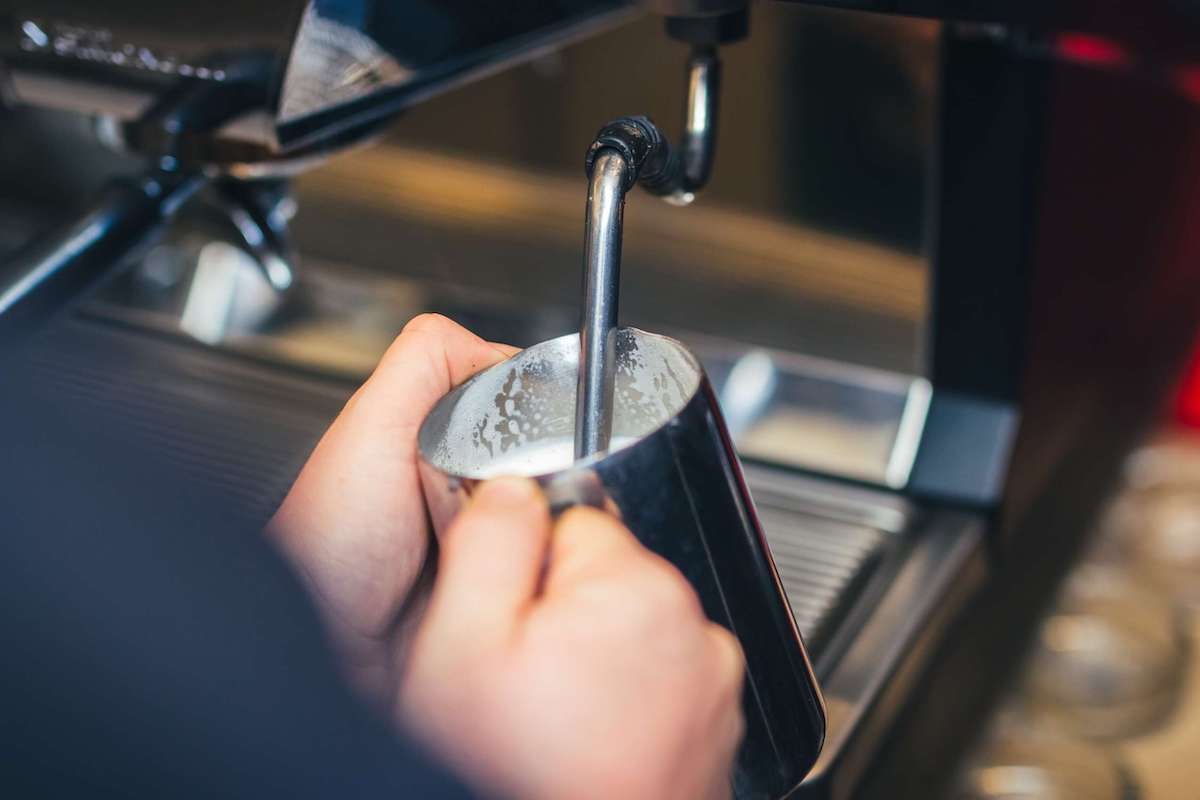 Hands steaming milk with an espresso machine