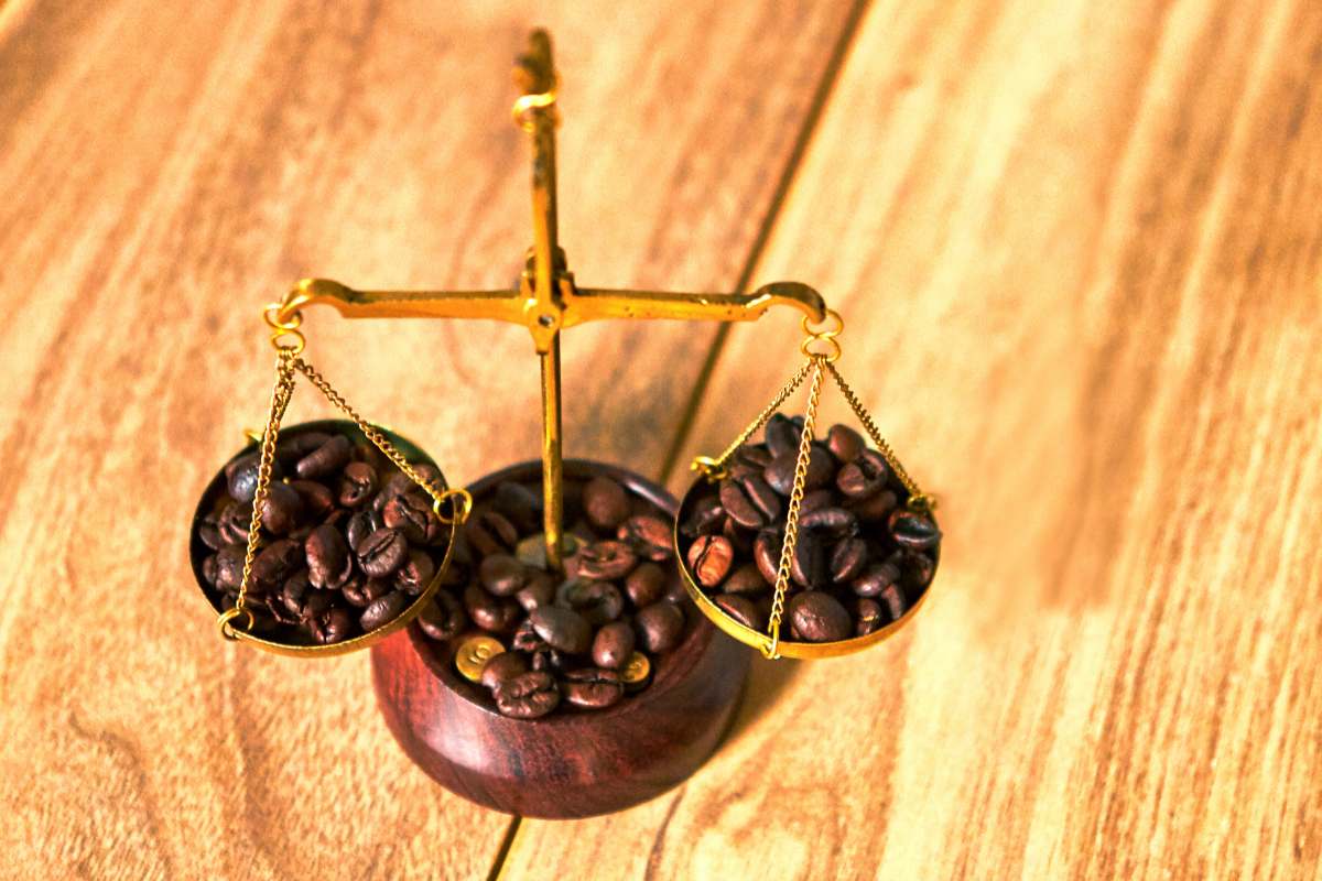 Coffee beans balance on the two plates of an old-style scale