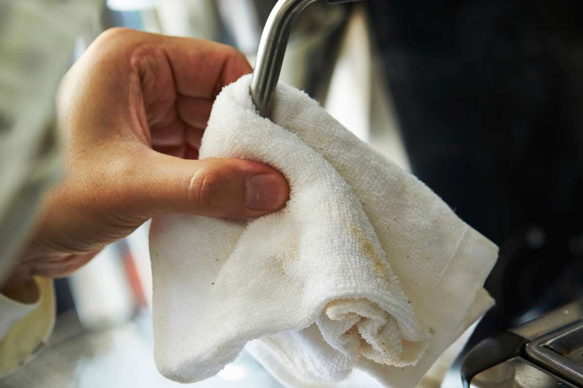 Hand wipes steam wand on an espresso machine