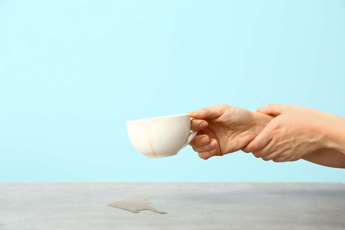 Shaking hand holding a coffee cup and spilling some coffee