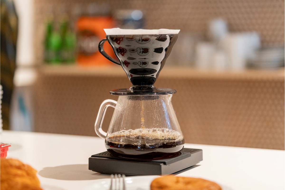 Pour-over coffee dripping into a carafe on a kitchen scale