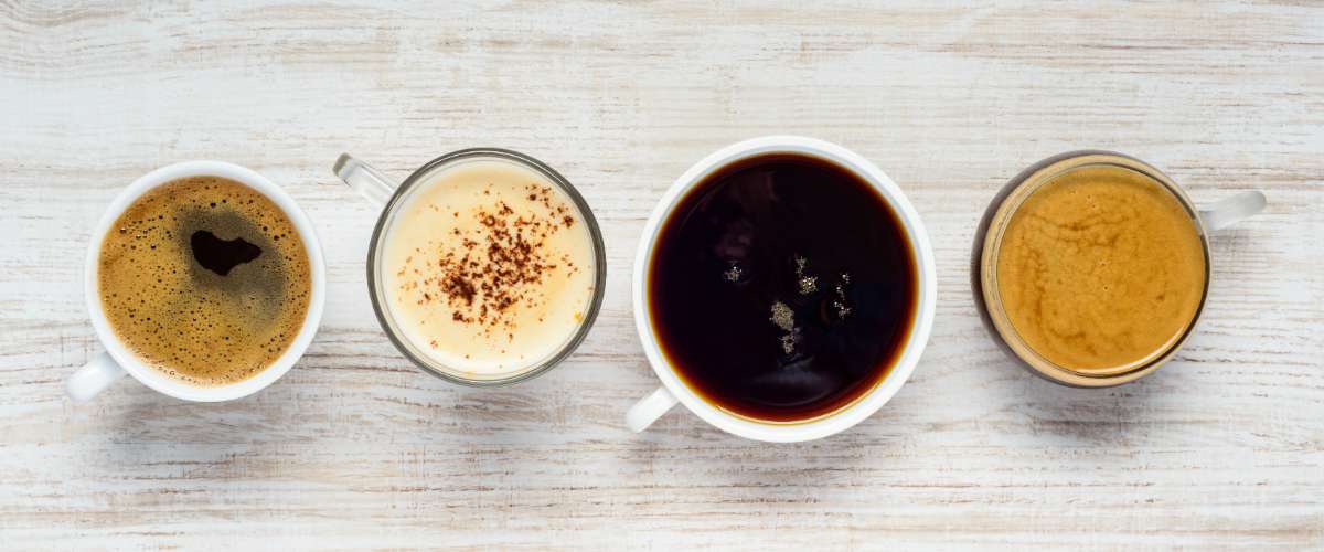 Four different coffee drinks lined up on a counter, viewed from overhead