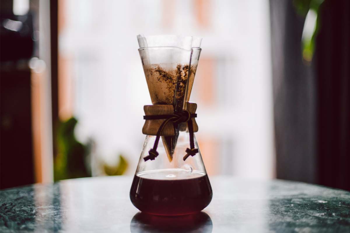 A paper filter dripping coffee into a Chemex carafe