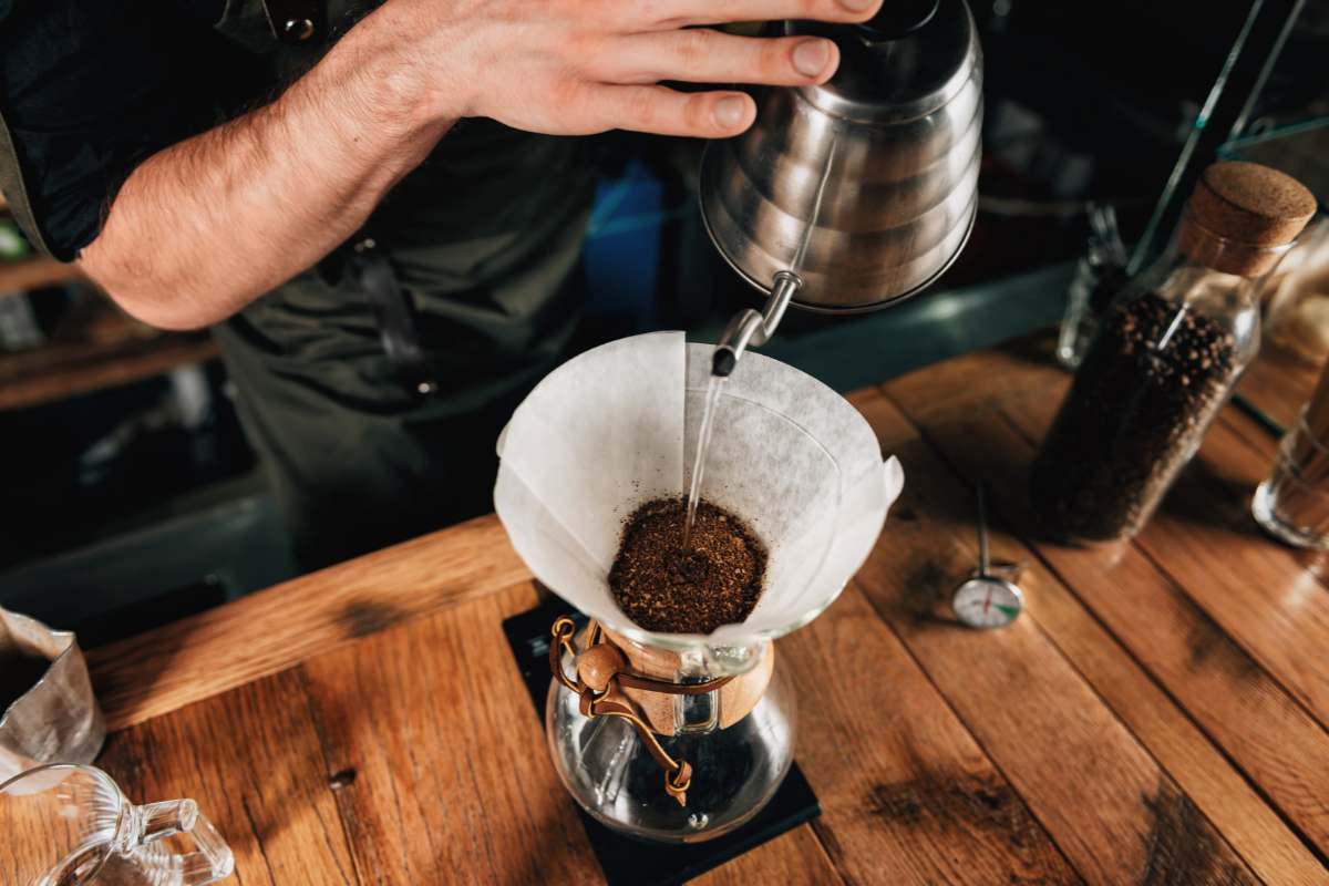 Barista pouring water from a gooseneck kettle into a pour-over cone