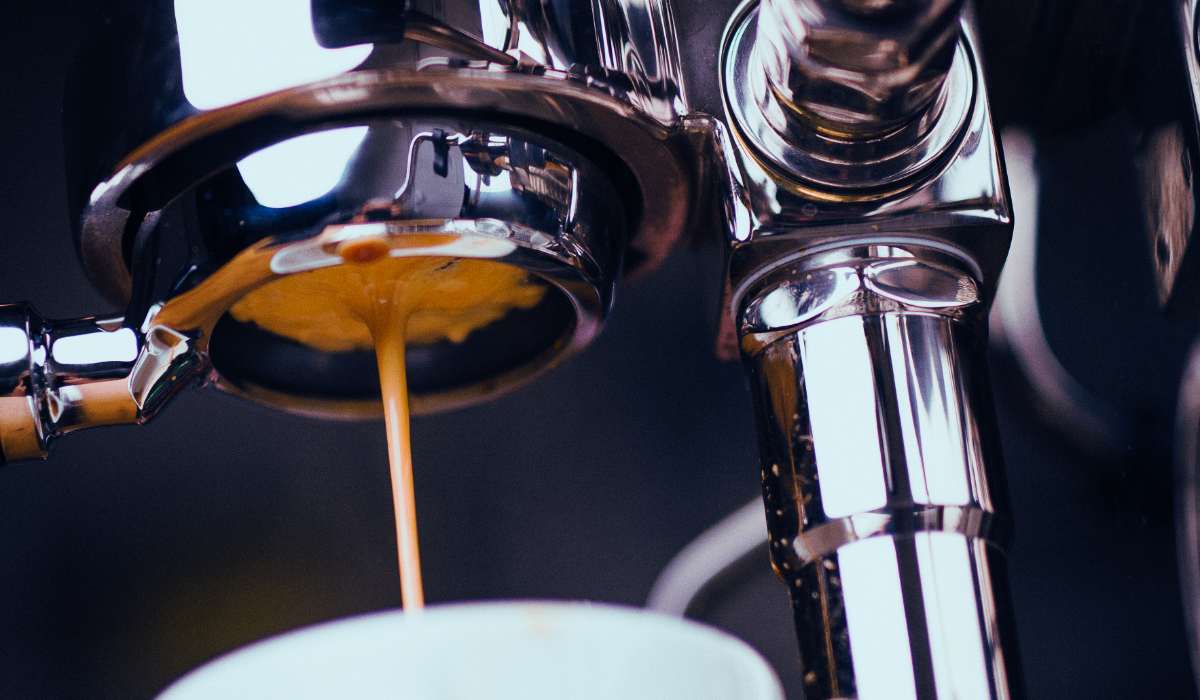 Closeup shot of espresso dripping from the bottom of a portafilter while brewing