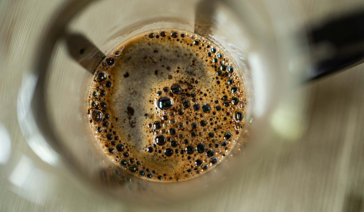 Overhead shot of ground coffee immersed in hot water in a French press