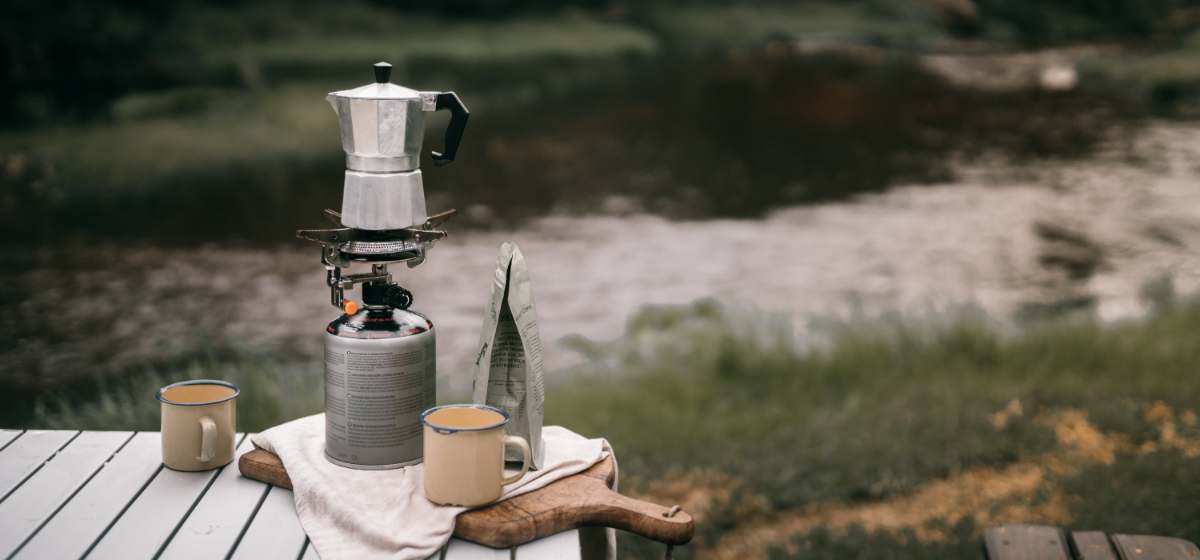 Moka pot resting atop a propane camping stove at a campsite