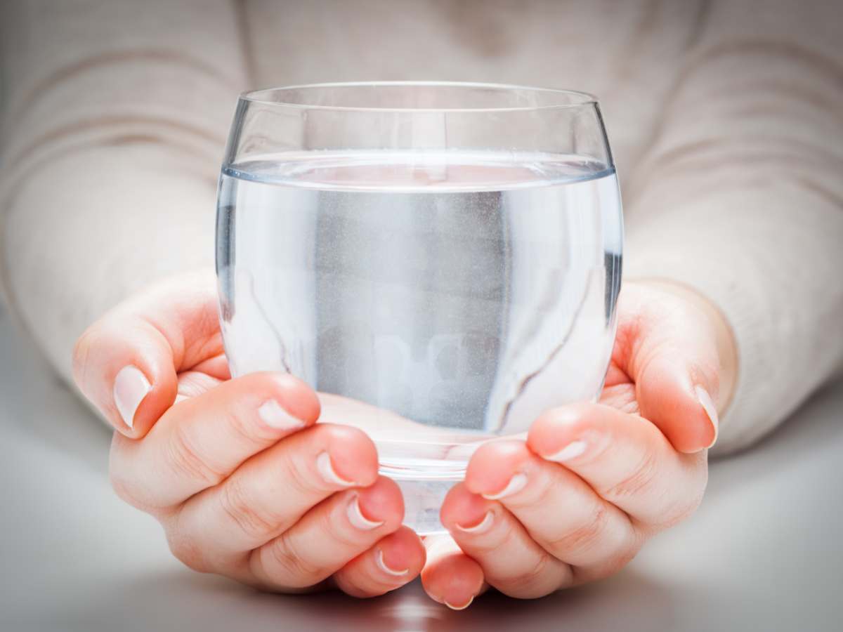 Woman's hands holding out a very clear glass of water